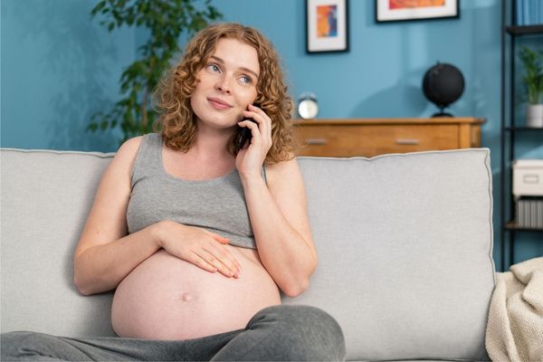 Schwangere mit Baby und Telefon